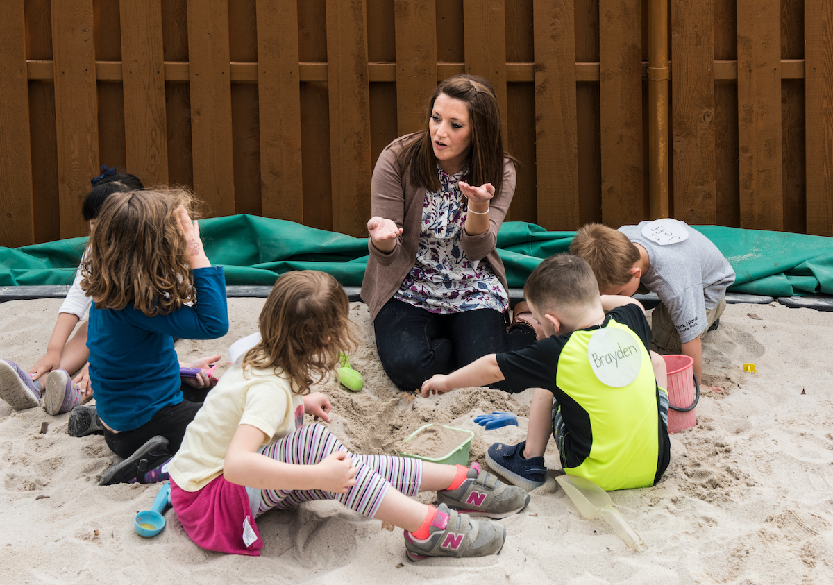 teacher in sandbox with students