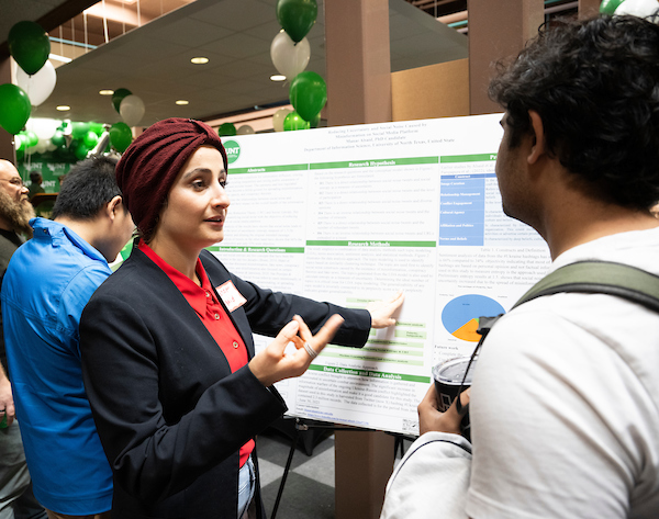 A student presenting her research poster at a conference