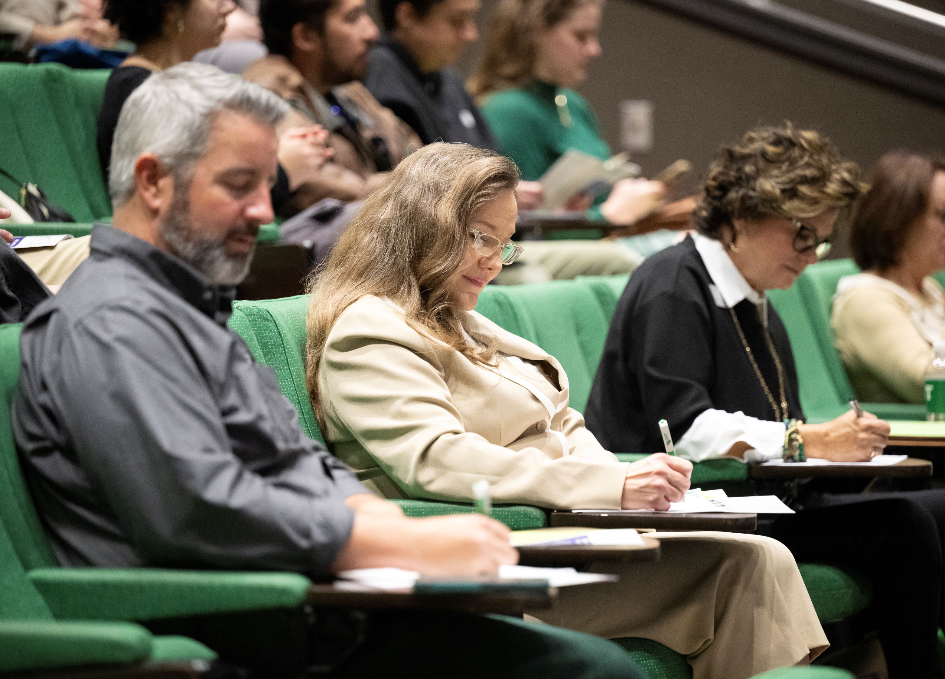 People writing notes in lecture hall