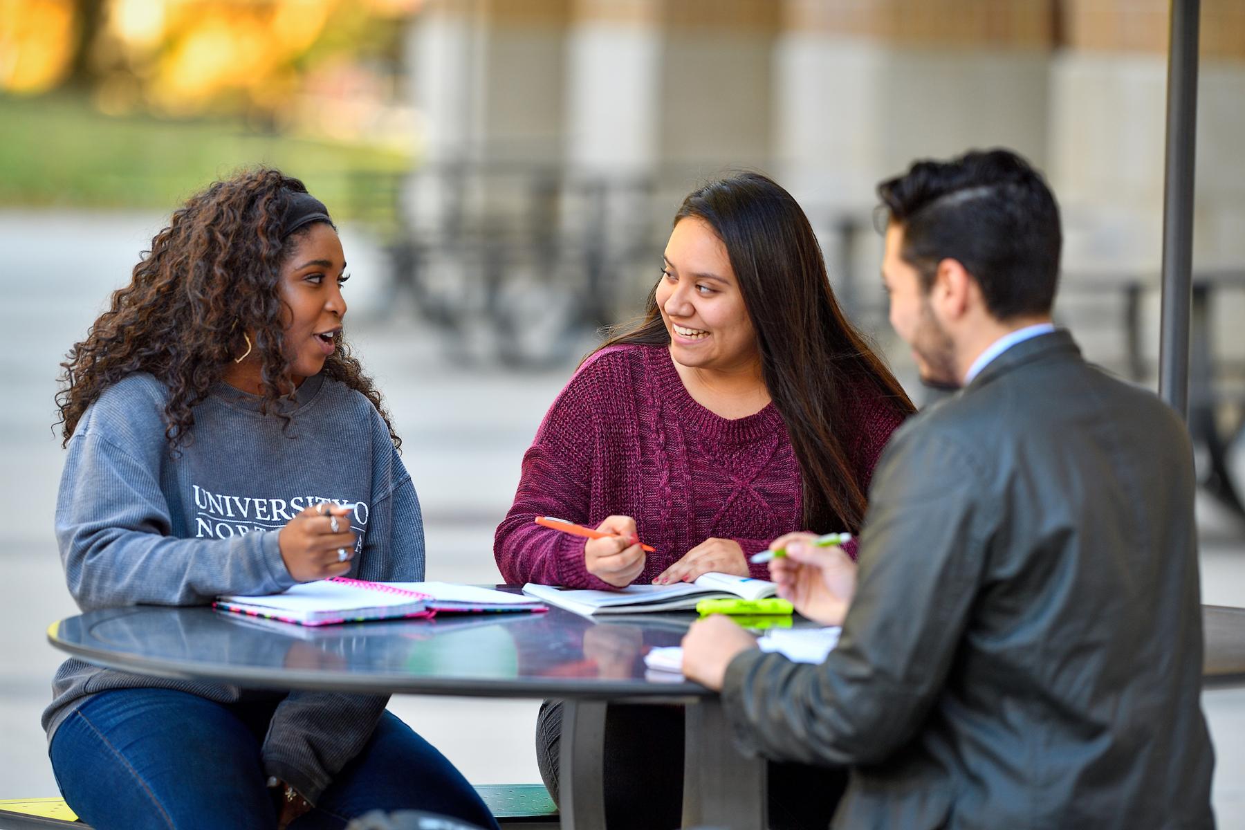 3 students sitting at outdoor table